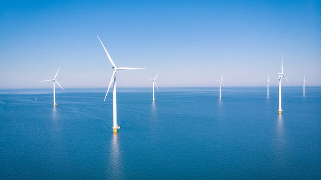 Offshore Windmill farm in the ocean Westermeerwind park, windmills isolated at sea on a beautiful bright day Netherlands Flevoland Noordoostpolder. Huge windmill turbines