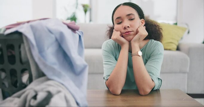 Bored, thinking and a woman in her home for laundry or cleaning during housework or chore responsibility. Depression, sad and burnout with a young cleaner in an apartment living room for housekeeping
