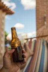 Unrecognizable person relaxing with a beer on his hammock. Vertical point of view shot of an...