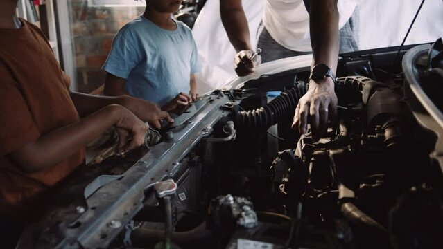 African Father Teaches Sons to Fix Vehicle in the Garage