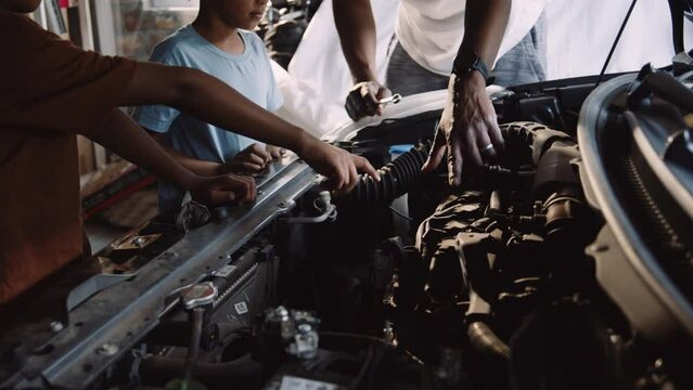 African Father Teaches Sons to Fix Vehicle in the Garage