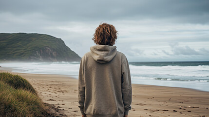 a person stands on a beach on a coast and looks out to sea. depression and mental illness concept.
