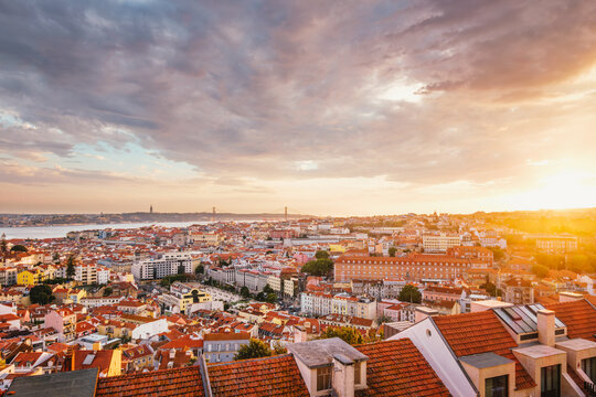 View of Lisbon famous view from Miradouro da Senhora do Monte tourist viewpoint of Alfama and Mauraria old city district, 25th of April Bridge at sunset. Lisbon, Portugal