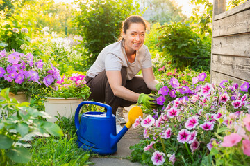 Gardening and agriculture concept. Young woman farm worker gardening flowers in garden. Gardener...