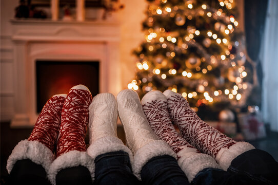 Close up of family feet with christmas socks warming up by the fireplace