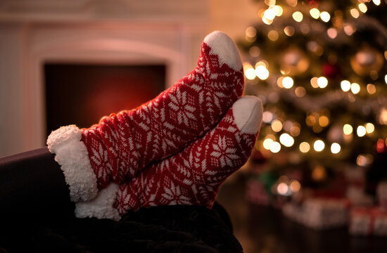 Close up of female feet with christmas socks, warming up by the fireplace