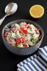 Homemade Tomato Cucumber Feta Salad in a Bowl on a black background, side view.