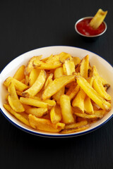 Homemade French Fries on a Plate on a black background, side view.