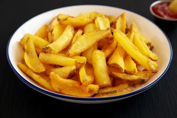 Homemade French Fries on a Plate on a black background, side view.