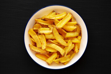 Homemade French Fries on a Plate on a black background, top view.