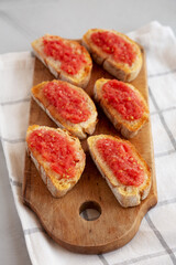 Homemade Pan Con Tomate (Tomato Toast) on a Rustic Wooden Board, side view.