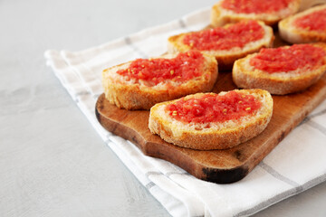 Homemade Pan Con Tomate (Tomato Toast) on a Rustic Wooden Board, side view. Copy space.