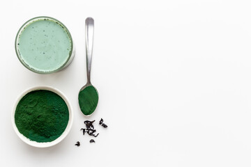 Spirulina algae powder in bowl and cold milk latte drink, top view