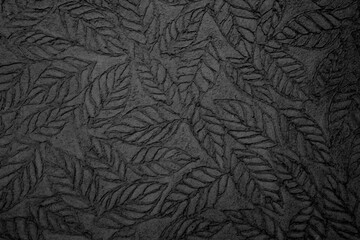 Leaf pattern stamped on chalkboard texture, handmade black background.
