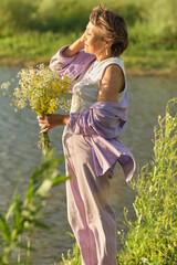 strong connection of an elderly woman with nature is evident as she sits in a meadow, holds wild flowers, and immerses herself in the world around