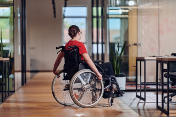 A modern young businesswoman in a wheelchair is surrounded by an inclusive workspace with glass-walled offices, embodying determination and innovation in the business world