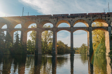 Fototapeta premium Railway Bridge with river in Bietigheim-Bissingen, Germany. Autumn. Railway viaduct over the Enz River, built in 1853 by Karl von Etzel on a sunny summer day. Bietigheim-Bissingen, Germany. Old
