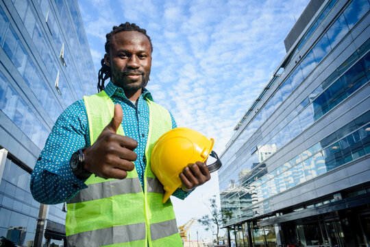 happy positive man young civil engineer of african ethnicity looking at camera smiling with thumb up