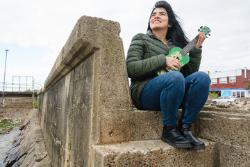 young venezuelan woman very happy enjoying weekend with her ukulele