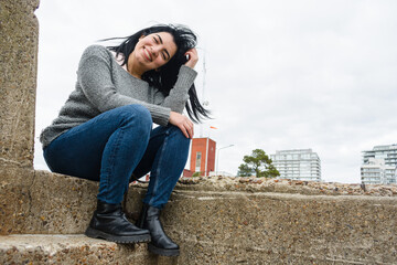 young latin woman sitting outdoors enjoying day happy smiling