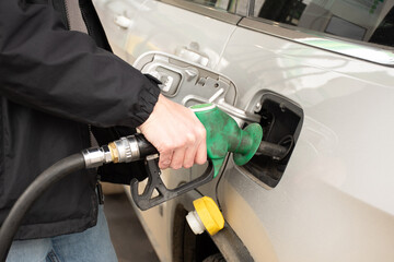 A man hand holding pump filling gasoline. Pumping petrol into the tank. A car refuel on gas station