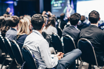 Speaker giving a talk in conference hall at business event. Rear view of unrecognizable people in audience at the conference hall. Business and entrepreneurship concept
