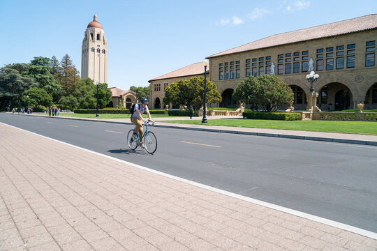 California, USA - May 15, 2018: view from a boulevard hoover tower among trees and school buildings against blue sky in distance on school campus with a man riding bike