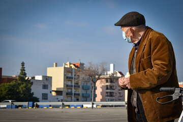 Anciano con mascarilla troceando pan en la calle