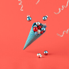 A turquoise ice cream cone, levitating and filled with Christmas ornaments, set against a red...