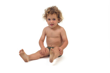 front view of a happy boy in underpants sitting on the floor on white background (3 year old)