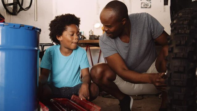 Mixed race father and son fixing motorbike in the garage together