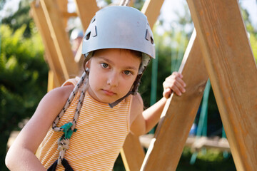 Little Girl Having Fun in a Rope Park Trail Facility. Happy little child enjoying climbing in an...