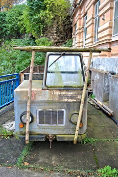 Abandoned, rusty, vintage, immobile utility vehicle covered by moss . 