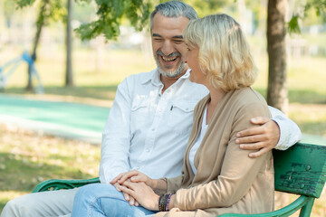 Obraz premium Happy elder love couple huge and smiling in romance sitting in park