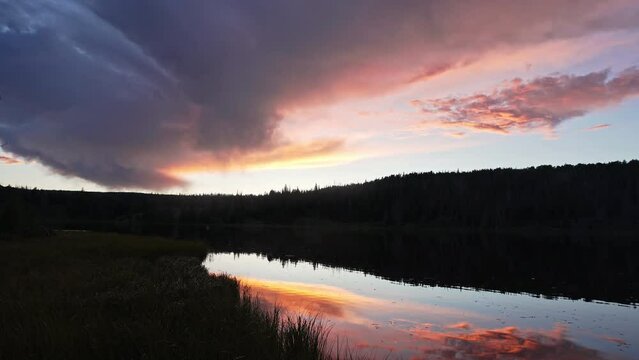Tilting down from sky to lake reflecting colorful sunset at Lyman Lake.