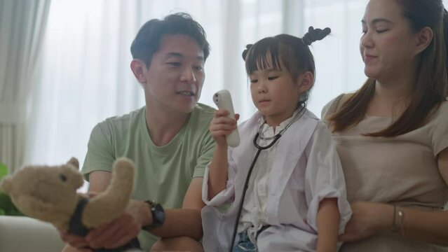 happy asian family mother father and kids at home on couch.