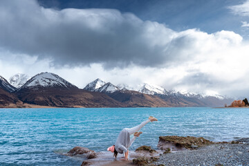Asian female yogi practice yoga at the beautiful scenic sunrise view of Lake Pukaki east bank, with...