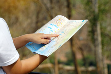 Thai female tourist looking through an atlas in Thailand, Thai version, check travel routes before continuing your mountain trip. Soft and selective focus.  Soft and selective focus.