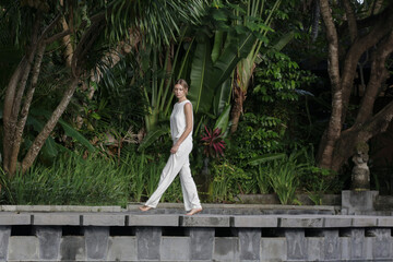 Outdoor portrait of stylish fashionable woman in white linen outfit in tropical resort. Natural...