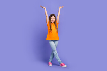 Full size photo of cute schoolgirl wear stylish t-shirt denim trousers hold arms up demonstrate...
