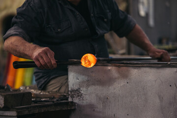 Unrecognizable craftsman with glassblower at workshop