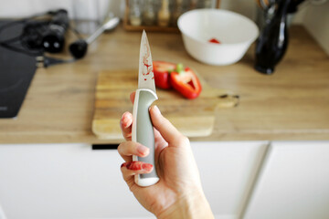 Woman cut her little finger with a knife while cooking vegetable salad on the kitchen. Female hand...
