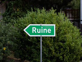 Obraz premium Ruine (ruin) sign to guide tourists to an ancient building. Signpost with an arrow to the left. Sightseeing as an attraction and travel destination.