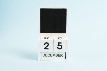 Christmas, wooden calendar with the date December 25 on a blue background with copy space. The concept of preparing for the celebration of Christmas and New Year and plans for the future.