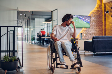Fototapeta na wymiar A sad businessman in a wheelchair occupies a hallway within a modern startup coworking center, embodying inclusivity and determination in the business environment