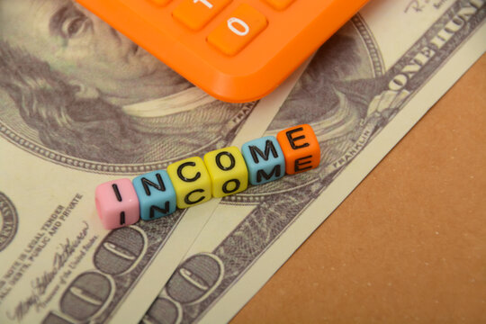 Calculator, money banknotes with text INCOME. Income represents the flow of funds into an individual's or entity's financial account