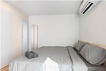 Fototapeta na wymiar White bedroom in minimalist style with a comfortable gray bed.