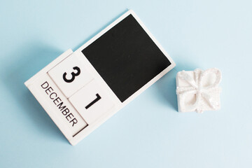 New Year, wooden calendar with the date December 31 on a blue background with decor, flatlay. The concept of preparing for the celebration of Christmas and New Year and plans for the future.
