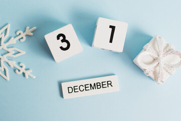 New Year, wooden calendar with the date December 31 on a blue background with decor, flatlay. The concept of preparing for the celebration of Christmas and New Year and plans for the future.