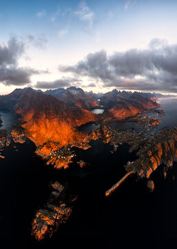 Aerial panoramic view of the coastal village of Tind framed by mountains at sunset, Lofoten Islands, Nordland, Norway, Scandinavia